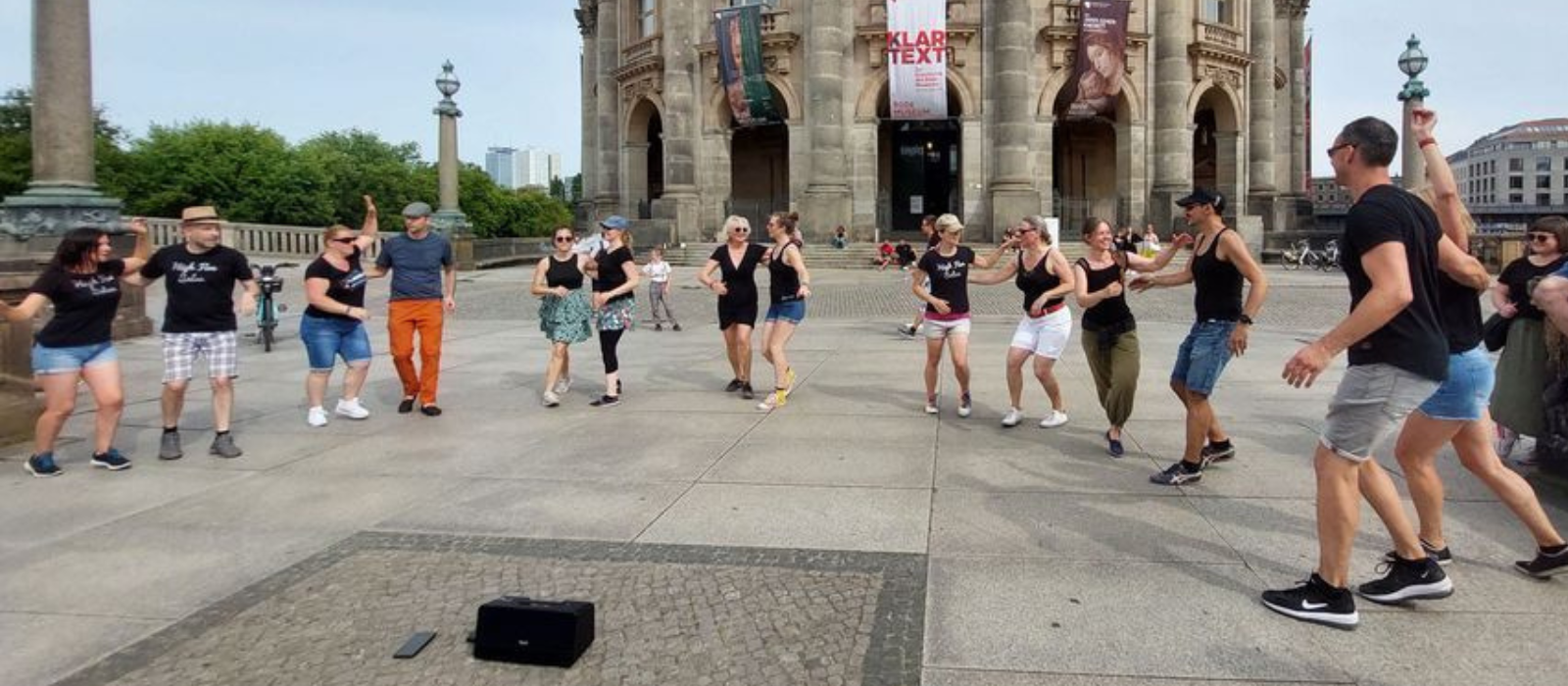 Group of people dancing Rueda de Casino on a sunny day in front of historic building in Berlin